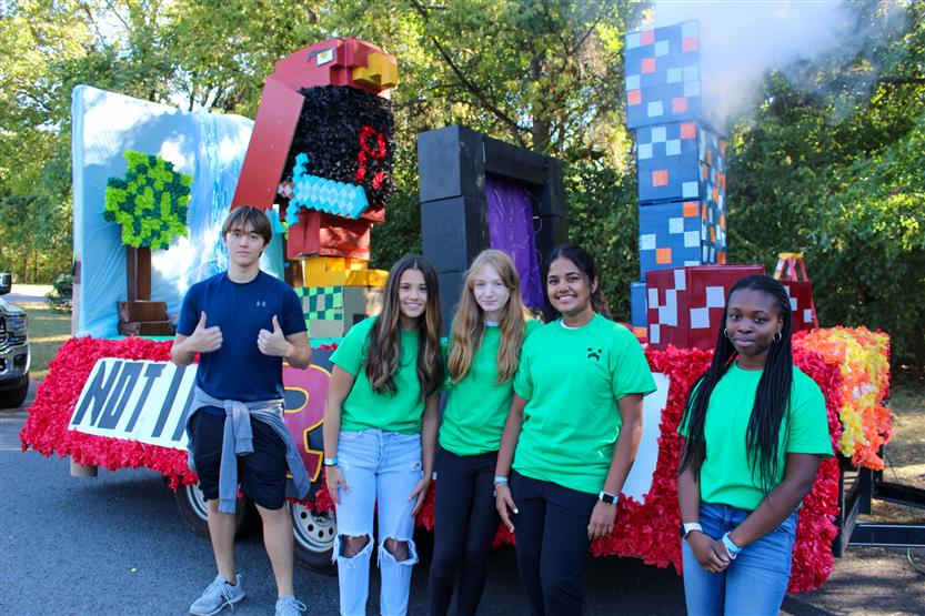 Students stand in front of a homecoming parade float